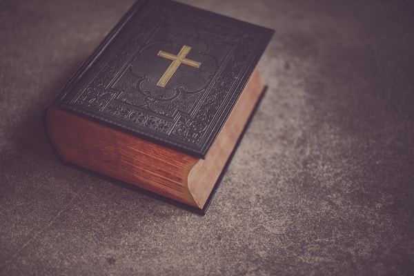 Zavřená bible ozdobená zlatým křížem.