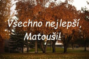 Nápis "Všechno nejlepší, Matouši!" na pozadí stromů se žlutým podzimním listím.