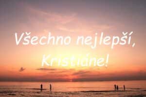 Nápis "Všechno nejlepší, Kristiáne!" na pozadí lidí na okraji moře na pláži při západu slunce.