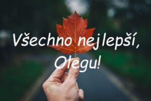 Nápis "Všechno nejlepší, Olegu!" na pozadí ruky držící podzimní list.