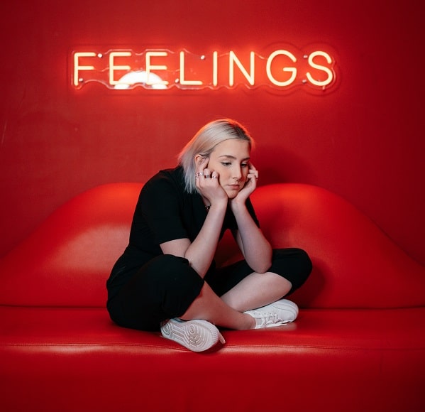 Smutná dívka sedící pod nápisem Feelings